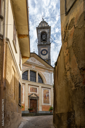 Historic bell tower and facade of the Church of Sant'Eusebio in the center of Pasturo, Italy. A striking glimpse between the village buildings.