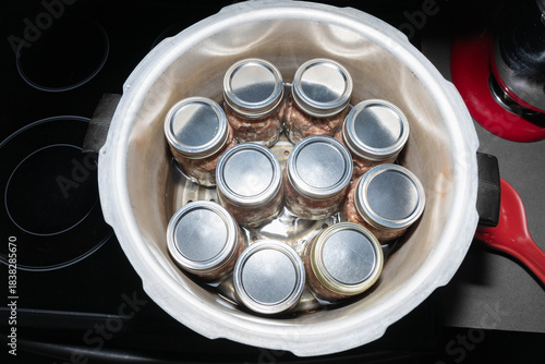Top view of ten, pint jars filled with pork sausage in a canner on a stove