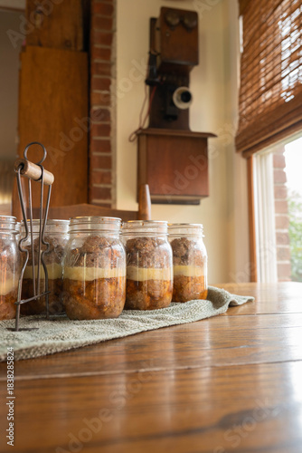 Sausage home canned in glass pint jars on kitchen table near a window