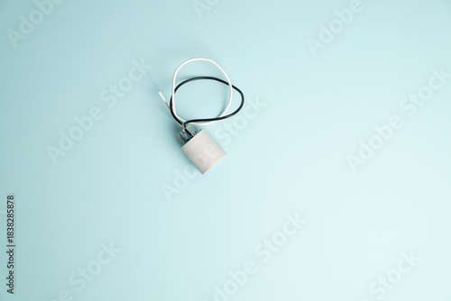 Side view of a new, replacement light socket with white and black wires, on bright blue background