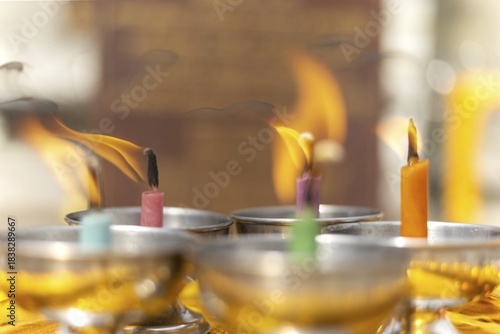 Oil lamps lit by believers as a symbol of the light of wisdom (the light dispels darkness and ignorance) in front of a Buddha statue, Wat Yannawa in the Sathon district, Bangkok, Thailand