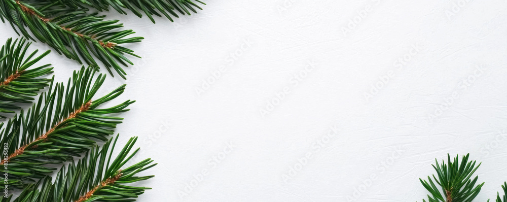 Obraz premium Christmas minimal background with green fir branches on white surface creating calm festive atmosphere