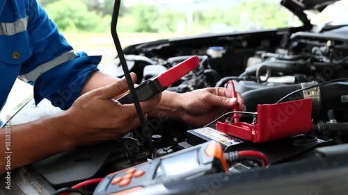 Service man to check car battery voltage, technician using multimeter, auto electrical check, vehicle maintenance service, close up diagnostic tool