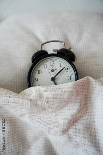 Canvastavla Black analog alarm clock under a blanket Close-up, soft light, fabric texture