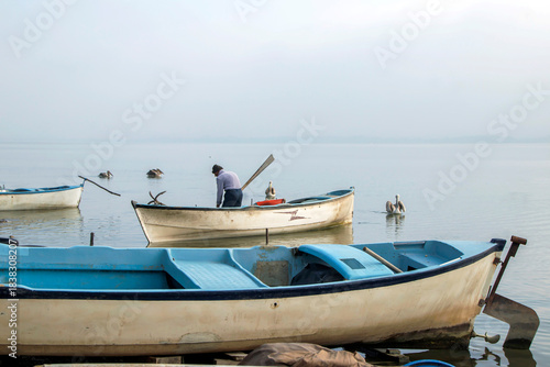 Fototapeta Naklejka Na Ścianę i Meble -  fishing man and  fishing boats on the lake shore, golyaka bursa 