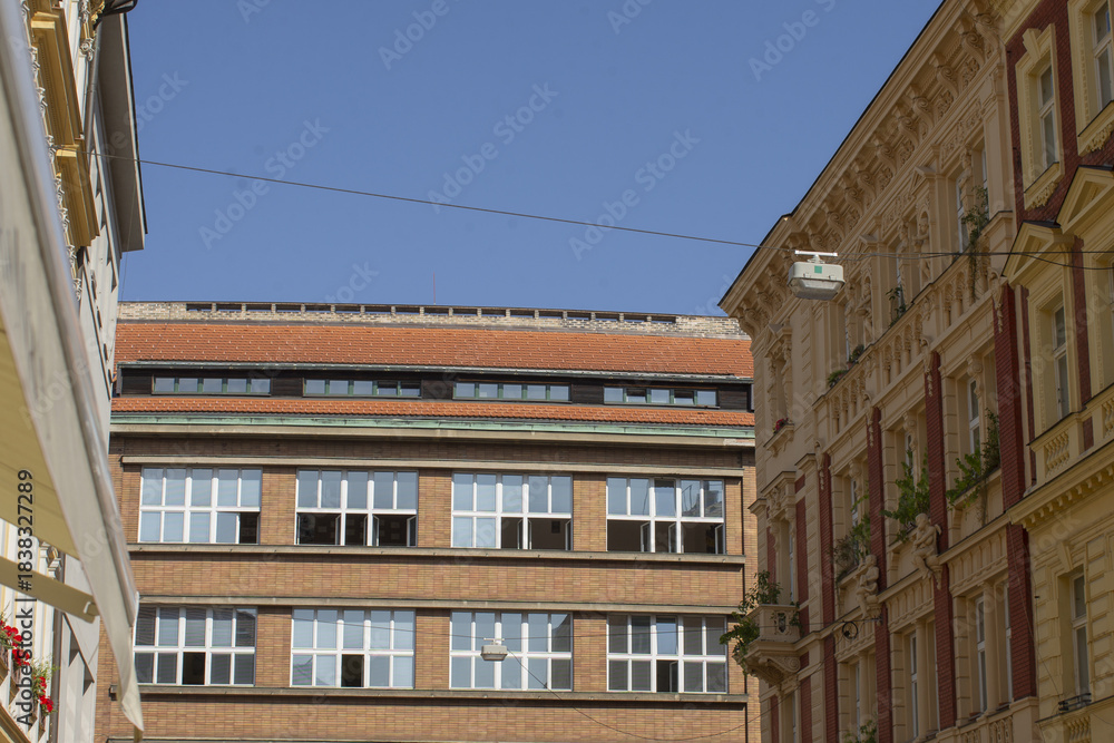 Obraz premium contrasting modern and historic facades with brick office block facing ornate classical building, rooftop line and cherub