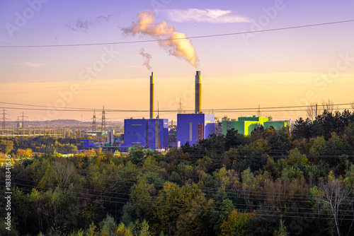 Über ihnen steigen die Rauchfahnen in den weichen, goldenen Himmel auf, während die nackten Strommasten wie stählerne Spinnennetze über die Landschaft gespannt sind. Ein urkomischer Kontrast zwischen 