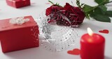 Displaying red rose lying on white tabletop, red gift box, lit candle, digital globe overlay
