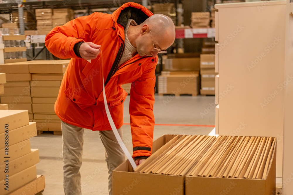 Fototapeta premium male customer measuring large flat cardboard boxes paper tape, self service furniture store warehouse aisle, home renovation interior, checking dimensions logistics planning, consumer shopping task