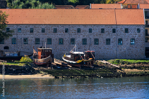 Traditional wooden boats resting on slipway beside historic stone warehouse along the Douro River, Portugal, Porto, 11 October 2025