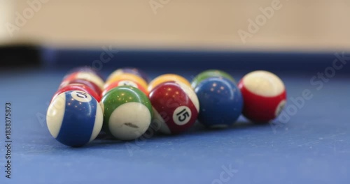 Cue striking cue ball initiating break shot on pool table balls shattering spreading toward pockets