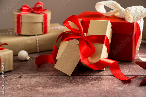 Festive Christmas craft gift boxes with red bows on wooden background