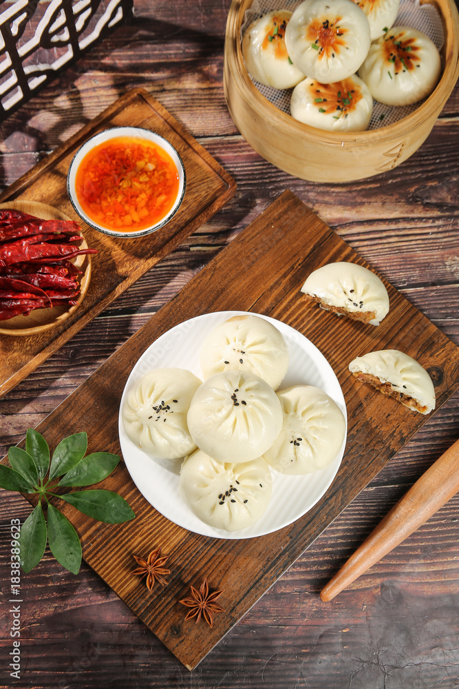 Fototapeta premium Traditional Steamed Meat Buns and Dumplings with Spicy Sauce on Rustic Wooden Background