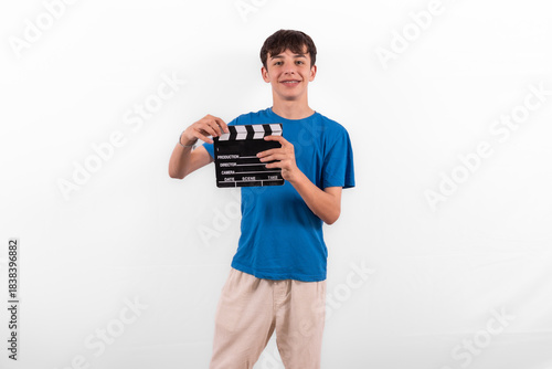 young happy casual dressed Generation Z influencer white male model teenage boy prepares to create and direct fun social media film reel with blank clapperboard slate. plain background studio setting