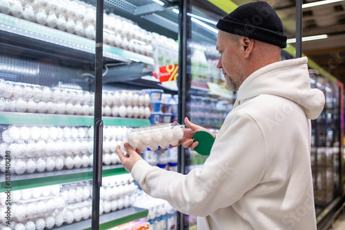 Man shopping in supermarket. A man buys eggs