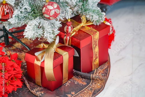クリスマスツリーの足元に置かれた赤いプレゼントボックスと装飾の室内冬景色／Red gift boxes and holiday ornaments under a Christmas tree in an indoor winter scene