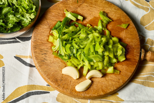 Leek and garlic. Cutting board with chopped leek and several cloves of garlic. There's also a bowl with some cilantro.
