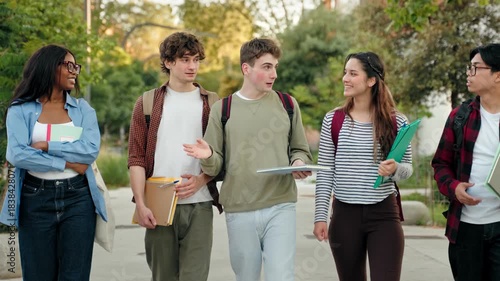 Group of student friends walking on college campus, chatting and laughing after university classes