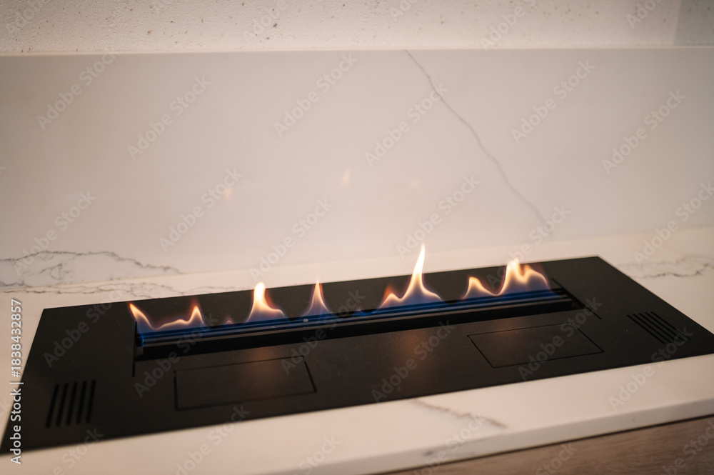 Obraz premium Automatic tabletop biofireplace. Burning eco bio ethanol fireplace built into white marble. Beautiful marble fireplace. Minimalist interior, alternative bio fireplot fireplace on ethanol gas.