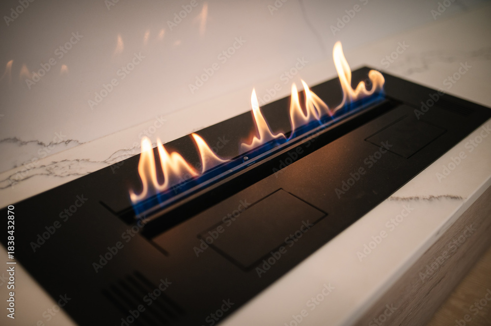 Obraz premium Automatic tabletop biofireplace. Burning eco bio ethanol fireplace built into white marble. Beautiful marble fireplace. Minimalist interior, alternative bio fireplot fireplace on ethanol gas.