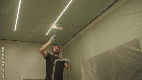 A man primes a drywall ceiling with a roller