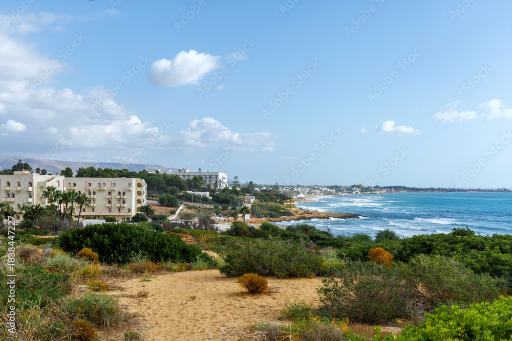 Fototapeta premium Sicily Italy seascape overlooking a turquoise bay and distant resort skyline.