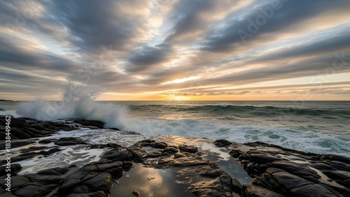Fototapeta Naklejka Na Ścianę i Meble -  Ocean wave crashing on rugged coastline at sunset with dramatic sky