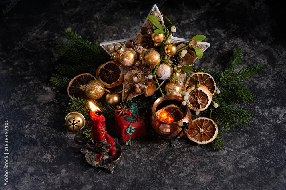 Naklejka premium Beautiful composition with festive decorations, burning candle, witch copper pot, fir branches on dark background. Witchcraft, magic ritual for Yule holiday, Winter solstice, winter seasonal fest.