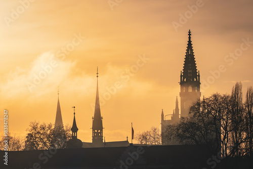The evening sun casts an orange glow on the clouds, turning the roof of the Steigenberger Hotel and the Cathedral 