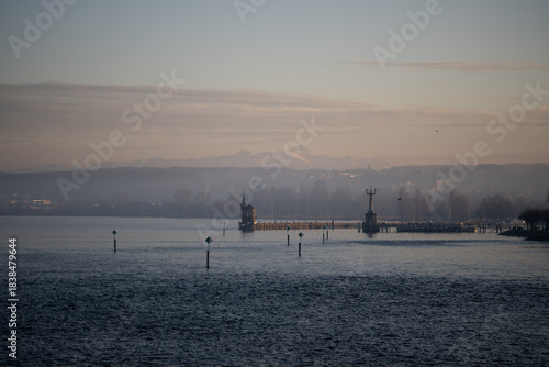 Lake Constance and Constance Harbor with snow-covered Säntis mountain in the background during a pastel-colored winter evening. Konstanz, Baden-Württemberg, Germany.