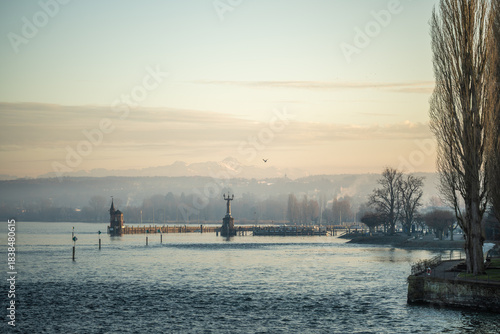 Lake Constance and Constance Harbor with snow-covered Säntis mountain in the background during a pastel-colored winter evening. Konstanz, Baden-Württemberg, Germany.