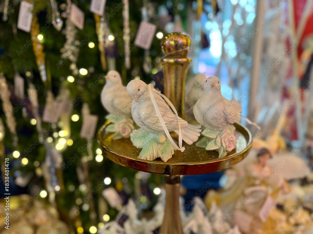 Naklejka premium Decorative white doves displayed on golden stand with holiday ornaments