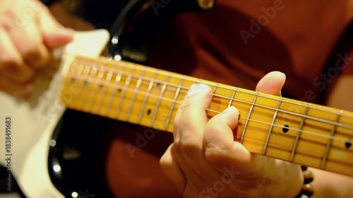 Closeup black and white colored old electric guitar and hands playing it