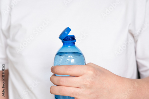 Vászonkép Close-up of a person holding a plastic bottle with a tethered cap, illustrating the EU’s new regulation requiring attached lids for improved recycling and reduced plastic waste