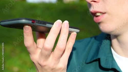 young beautiful redhead caucasian woman holds smartphone in hands, recording voice vessage