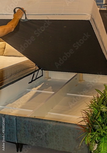 Open bed frame with raised mattress showing empty storage space inside