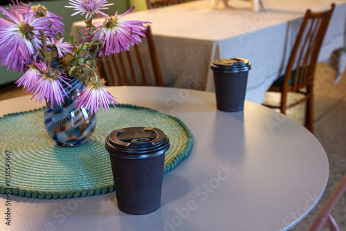 Brown closed takeaway coffee cups on a table in a cozy cafe.