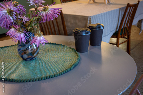 Brown closed takeaway coffee cups on a table in a cozy cafe.