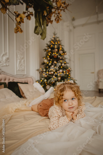 A charming 6-year-old blonde with curly hair in Christmas decorations 