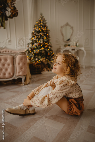 A charming 6-year-old blonde with curly hair in Christmas decorations 
