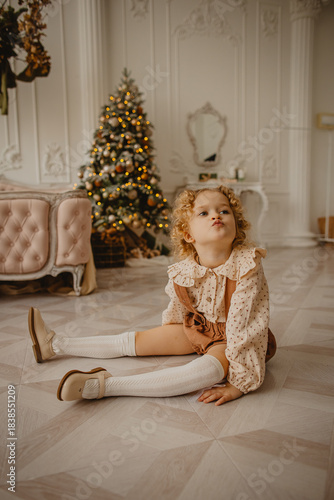 A charming 6-year-old blonde with curly hair in Christmas decorations 