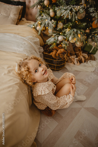 A charming 6-year-old blonde with curly hair in Christmas decorations 
