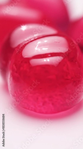 Extreme macro close up of vibrant red gummy candy texture with glossy highlights and soft focus background for sweet concepts