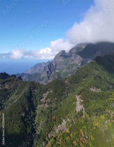 Mountainous landscape with lush green forests and rugged peaks, a glimpse of the ocean beyond