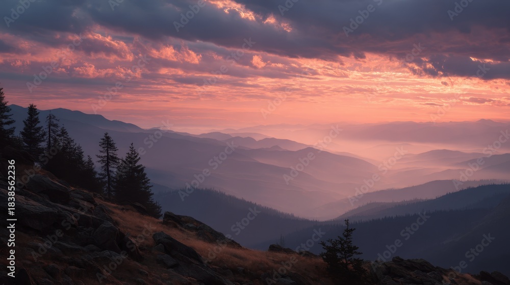 Obraz premium Bright colors fill the sky during sunset as mountains fade into the distance. Silhouettes of trees stand against the clouds creating a natural scene after a long day.
