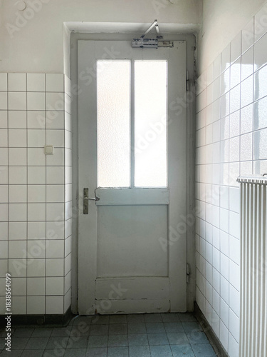 Bright, minimalist interior with a white door in a tiled, no person