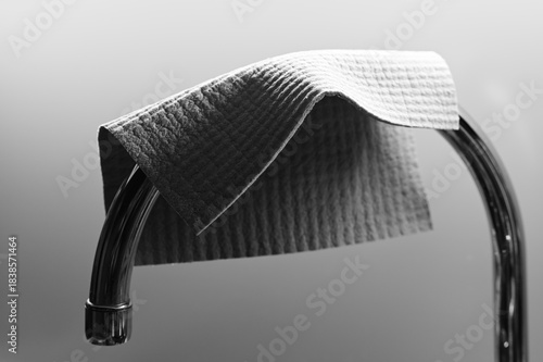 a textured cleaning cloth draped over a curved chrome bar