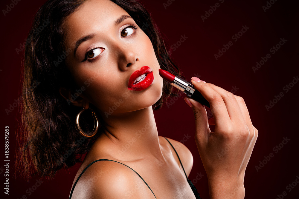 Obraz premium Elegant woman with stunning red lips applying lipstick in a glamorous fashion close-up