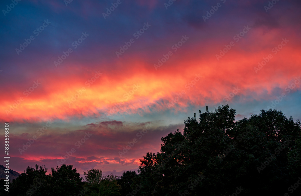 Fototapeta premium Clouds turn bright colors at sunset from wildfire smoke in the air