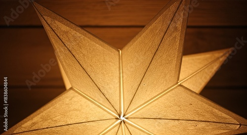 Close-up of a glowing, warm golden star-shaped paper lantern illuminating a dark room.